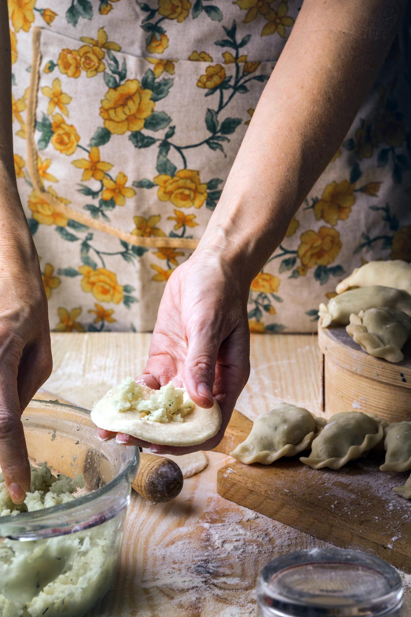 Hands kneading dough on a wooden board with herbs nearby